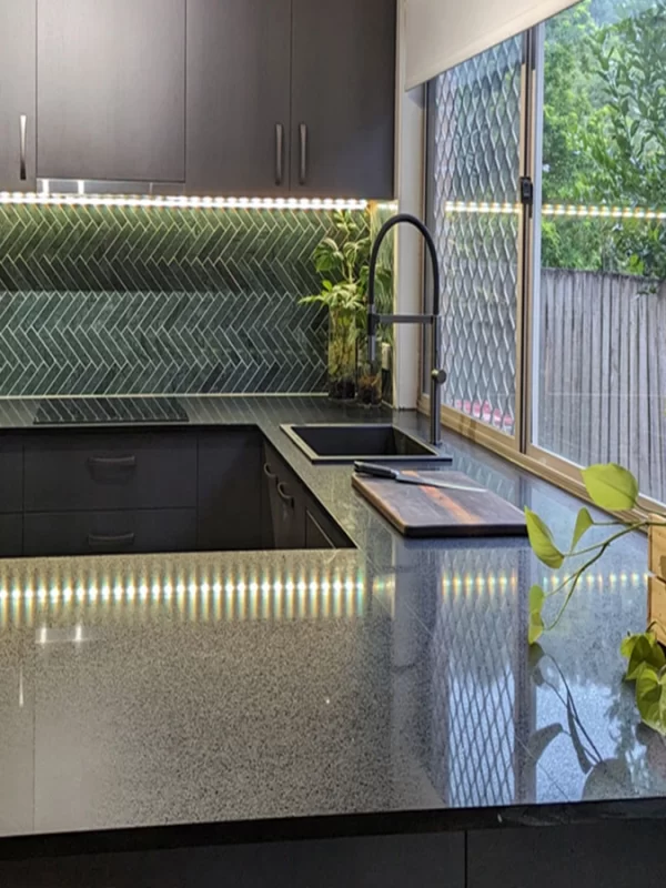 Kitchen renovation featuring cool green herringbone mosaic tiles illuminated by LED Lighting. by Gecko Kitchens in Brisbane.