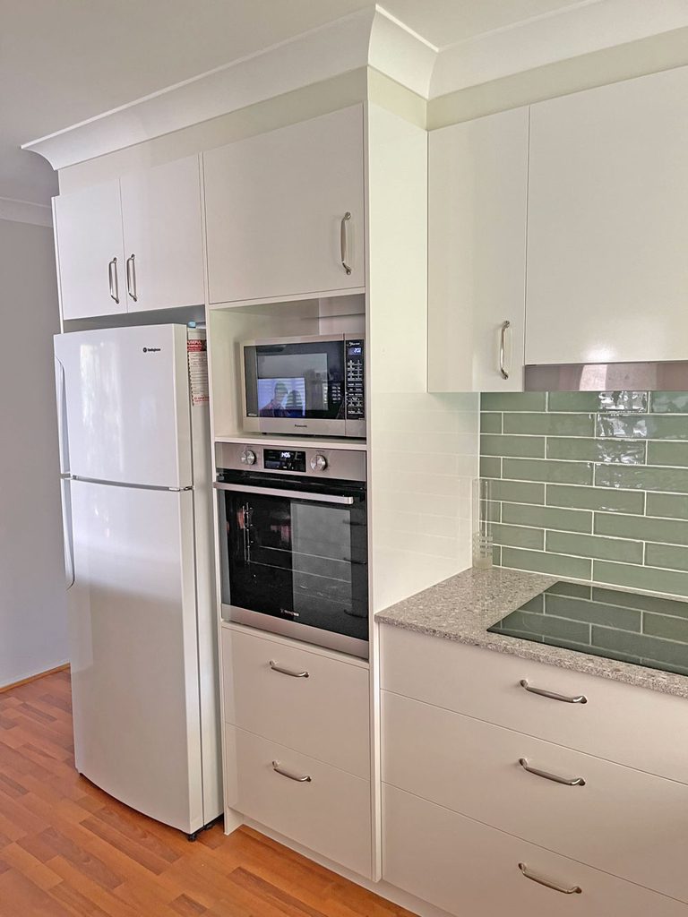 Modern kitchen renovation with white cabinetry, cool green tiles and elegant stone benchtop by Gecko Kitchens,