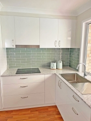 Sleek and modern kitchen renovation with cool green tiles by Gecko Kitchens