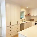 Tall kitchen cupboard with bifold doors and white cabinetry designed by Gecko Kitchens based in Upper Kedron.