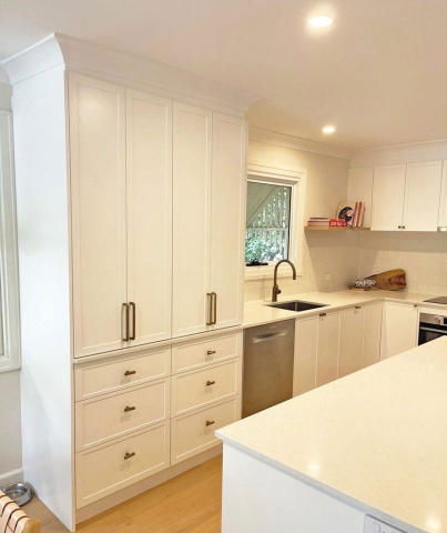 Traditional Kitchen in white, tall cupboard with bifold doors Kitchen cupboard with bi fold doors custom designed and installed by Gecko Kitchens Kedron