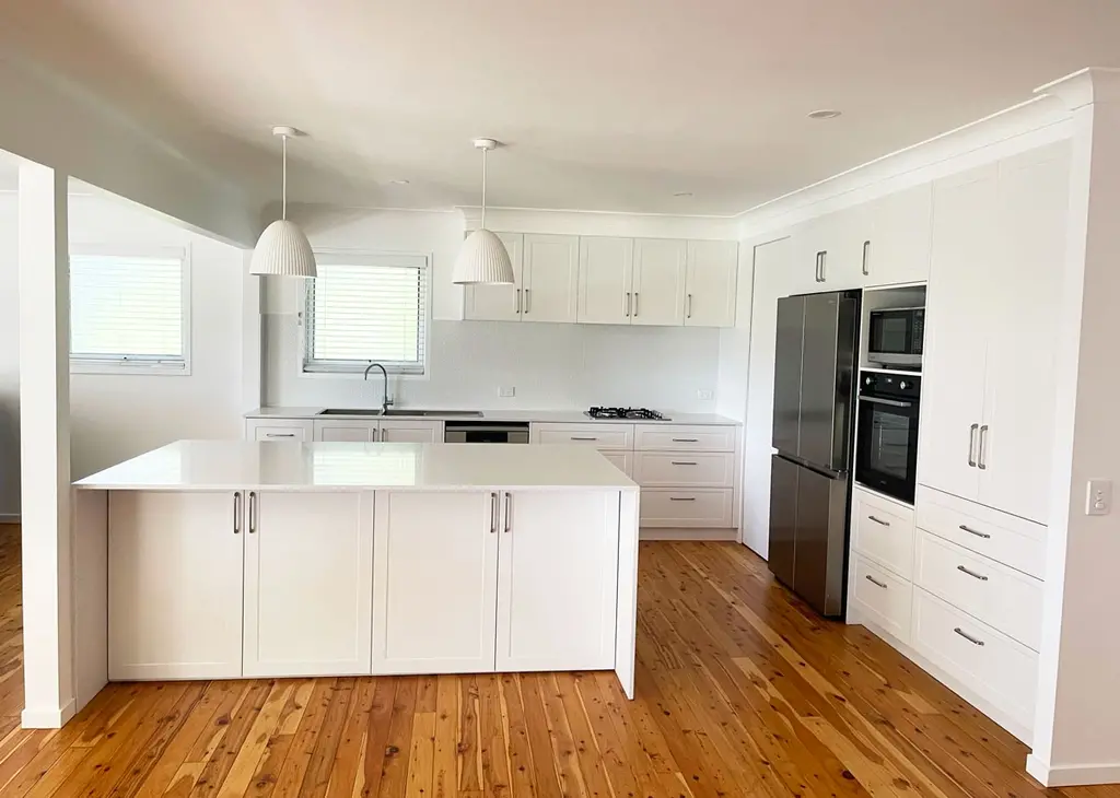 Open plan kitchen with white cabinetry, silica free stone benchtops by Gecko Kitchens, kitchen builder.