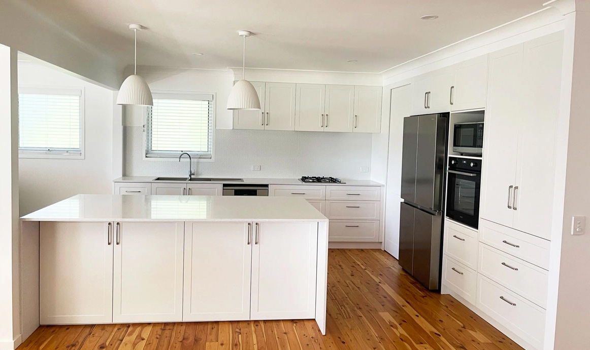 Open plan kitchen with white cabinetry, silica free stone benchtops by Gecko Kitchens, kitchen builder.